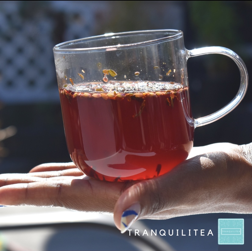 A person holding a glass of tea in their hand.