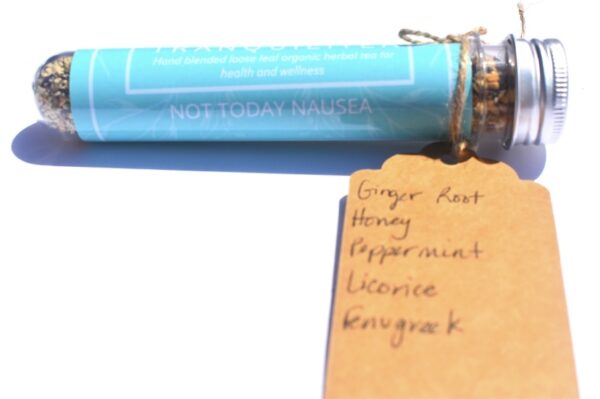 A blue tube of candy next to a tag with the words ginger root, honey, peppermint, licorice and koukrask.