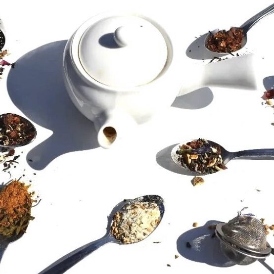 A white teapot and spoons with different types of food on them.